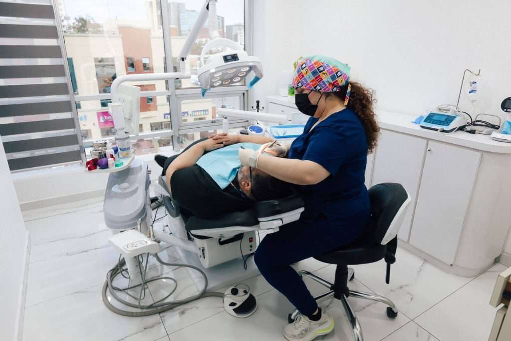 Dra. Evelyn Carolina Tirado Parra assisting a patient during a dental appointment in a modern clinic in Tijuana, Mexico.